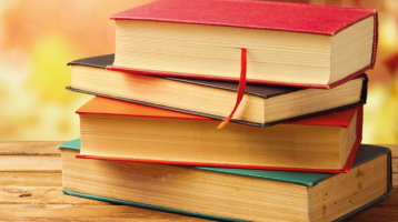 Cuatro libros en una torre, de diferente tamaño y color