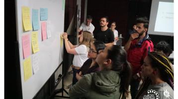 Personas aportando ideas en papeles de colores pegándolos en una pizarra