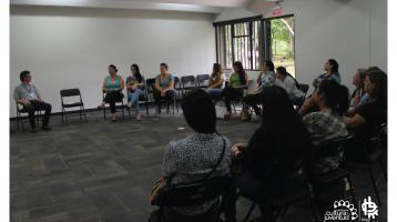 Grupo de personas sentados haciendo un semicírculo prestando atención a un asesor