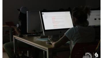 Muchacha en un salón tomando apuntes frente a una computadora