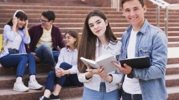 Estudiantes de pie con libros abiertos mirando hacia la 