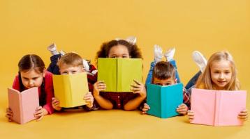 Grupo de niños cubriéndose la cara con libros
