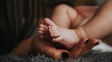 Manos de mujer sosteniendo piecitos de bebé