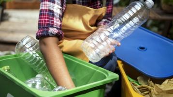 Manos de un hombre separando botellas de plástico reciclables