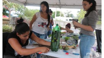 Una familia haciendo macetas con botellas plásticas 
