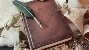 Pluma sobre un libro antiguo cubierto de pétalos de flores secas