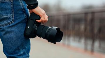 Mano masculina que sostiene una cámara fotográfica en la calle