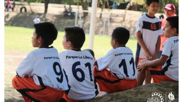 Grupo de niños prestando atención en un clase de fútbol