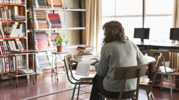 Bibliotecóloga sentada frente a un estante de libros