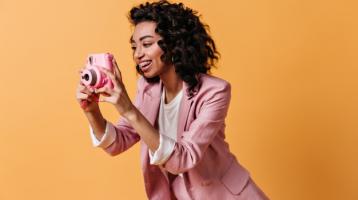 Mujer sonriente con chaqueta rosa, tomando una fotografía
