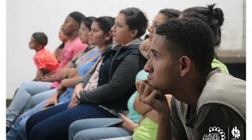 Grupo de personas prestando atención a una  charlista