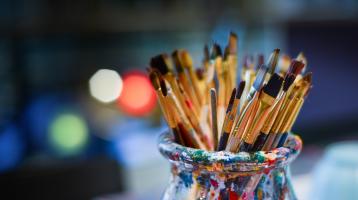 Frasco de vidrio manchado de pintura con pinceles. 