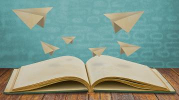 Libro abierto con aviones de papel. 