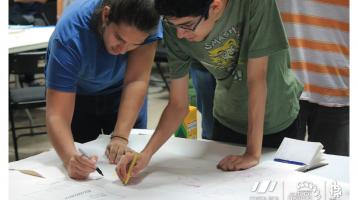 Dos personas escribiendo en un papel las cosas más importantes