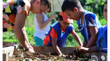 Un instructor y varios niños preparando la tierra para sembrar