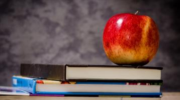 Una manzana sobre tres libros apilados. 