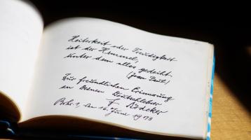 Libro abierto mostrando frases en letra cursiva. 