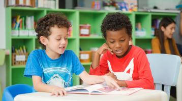 Dos niños leyendo un libro. 