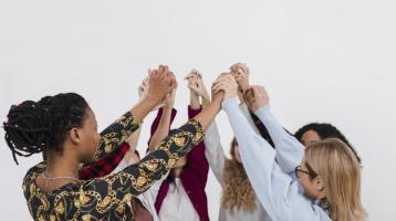 Grupo de mujeres tomadas de la mano en círculo. 