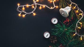 Fondo negro. Luces de navidad, cancelas y una guirnalda con una campana y bellotas.