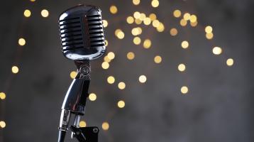 Fondo gris con luces de navidad. Micrófono moderno. 