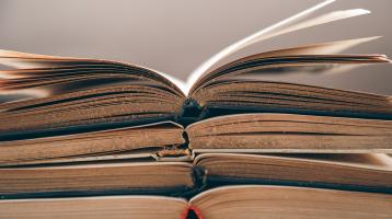 Cuatro libros apilados sobre un fondo borroso.