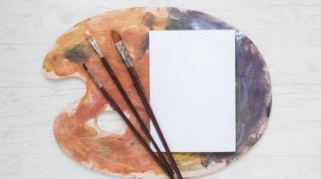 Libro blanco sobre paleta con pinceles.