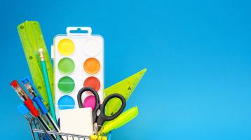 Fondo celeste. A la izquierda en un envase se encuentran diversos útiles escolares como: regla, tijeras, lápices, pinturas y lapiceros. 
