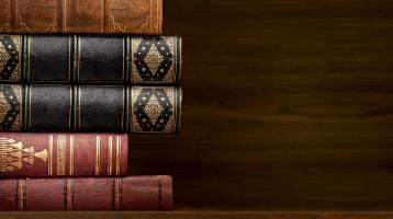 Fondo de madera. Sobre una mesa de madera, a la izquierda una torre libros antiguos.