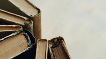 Sobre un fondo blanco, en el lado izquierdo varios libros antiguos.