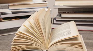 Fondo de torres de libros. Sobre una mesa de madera un libro abierto.