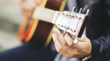 Persona sosteniendo una guitarra.