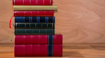 Fondo de madera. Sobre una mesa de madera una torre de libros de colores. 