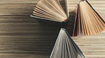 Sobre mesa de madera. Tres libros en vertical desde vista superior.