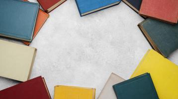 Fondo blanco. Desde vista superior libros de colores en los bordes.