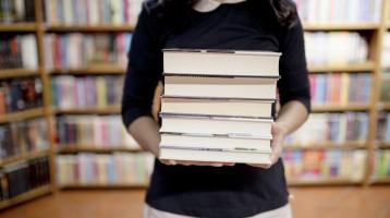 Mujer sosteniendo una pila de libros.