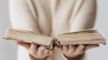 Persona sosteniendo un libro abierto. 
