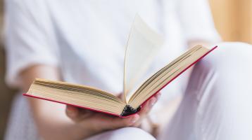 Persona sosteniendo un libro abierto. 