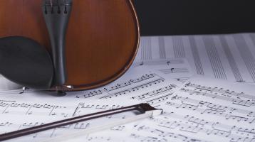 Violín en vertical sobre partituras musicales. 