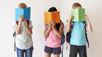 Grupo de niños con un libro en su cara.