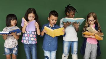 Grupo de niños leyendo un libro.