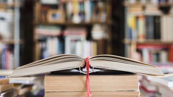 Fondo difuminado de una biblioteca. Libro abierto en primera plana.