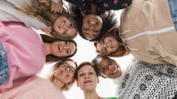 Grupo de mujeres formando círculo y mirando abajo. 
