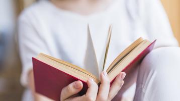 Mujer sosteniendo un libro abierto.