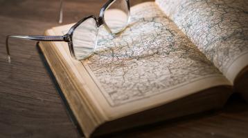 Un libro abierto y unos lentes sobre el libro