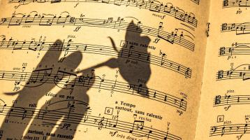 Una partitura y la sombra de una mano sosteniendo una flor