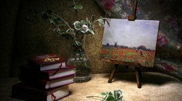 Unos libros apilados, un florero y un bastidor 