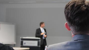 Persona de espalda viendo a otra que está exponiendo al frente
