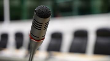 Un micrófono y de fondo unos asientos