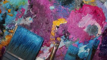 Varias brochas y pintura de varios colores esparcidas